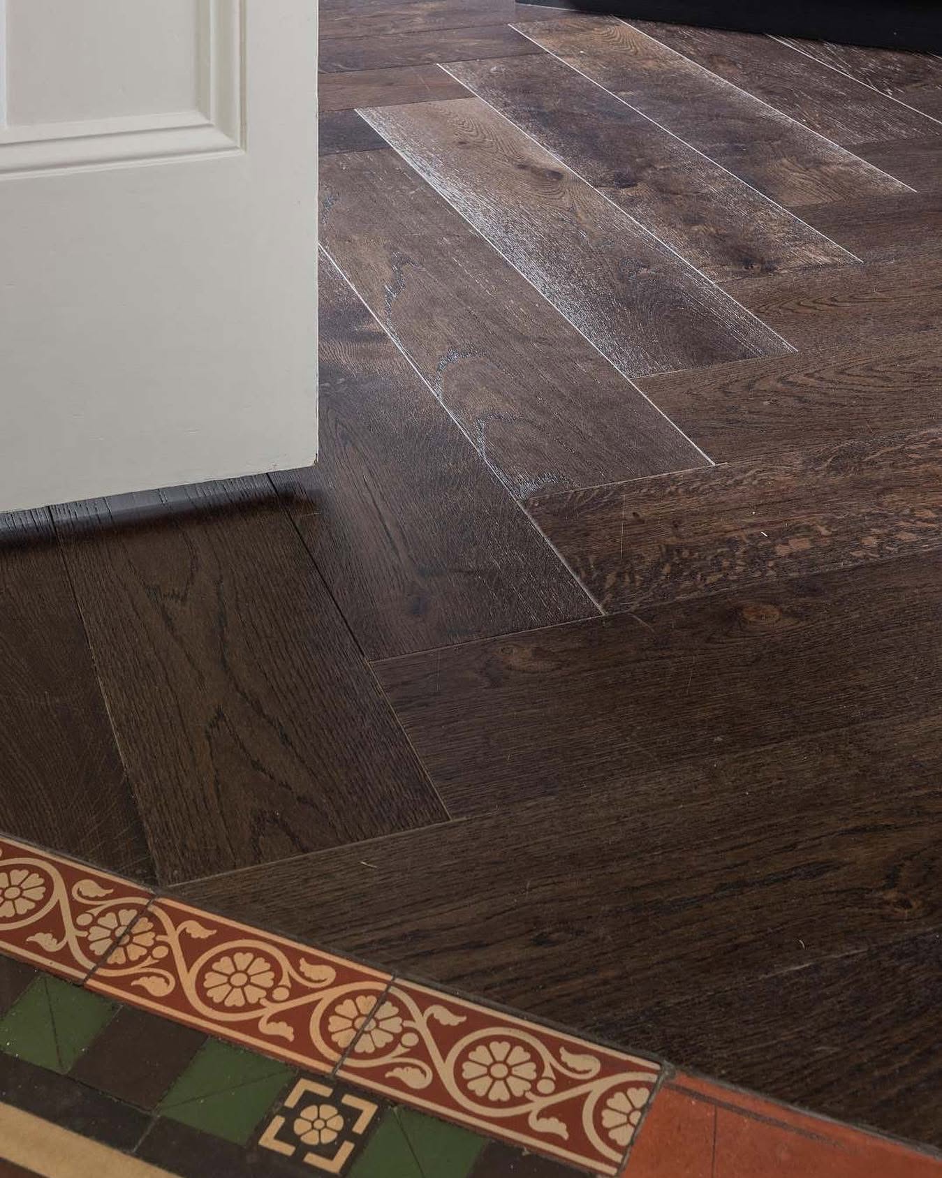 Dark oak boards meeting original tessellated tiles in a hallway